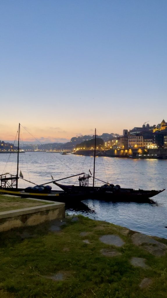 Rabelo boats floating on the Douro River as night falls in Porto